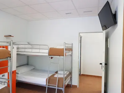 a room with bunk beds and a flat screen tv at Albergue Espiritu Xacobeo in O Pedrouzo