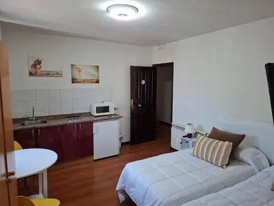 a bedroom with two beds and two paintings on the wall at Apartahotel portal de leon in Caboalles de Abajo
