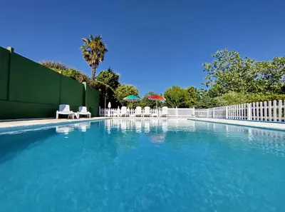 a swimming pool with chairs and umbrellas next to a fence at Villa Salgueiros in Teo