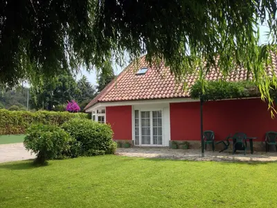 a red house with chairs in the yard at Villa Salgueiros in Teo