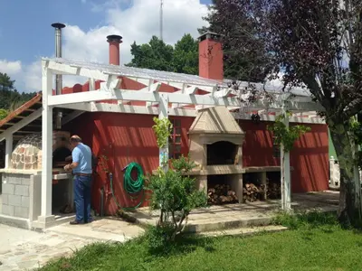 a man standing outside of a red building with a pizza oven at Villa Salgueiros in Teo