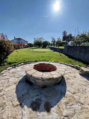 a stone fire pit in a park with a golf course at Villa Salgueiros in Teo