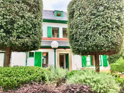 a green and white house with trees and bushes at Covas Seabreeze Cottage in Viveiro