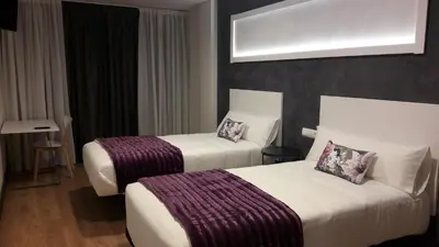 a bedroom with a large white bed with two pillows at Hotel Malecon in O Barco de Valdeorras