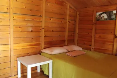a log cabin with a bed and a table at Camping Fragadeume in Monfero