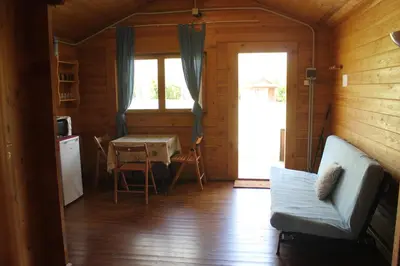 a living room with a table and a couch in a cabin at Camping Fragadeume in Monfero