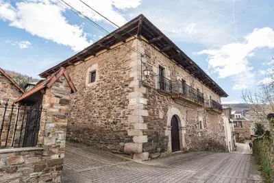 an old stone building with a balcony on a street at Casona Las Burillas in Villar de los Barrios