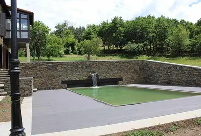 a fountain in front of a brick wall with a bench at Casa Pro Pantea in Monforte de Lemos