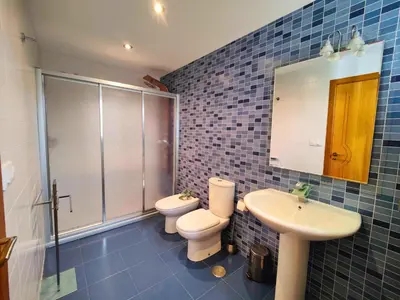 a blue tiled bathroom with a toilet and a sink at Casa-Nova 2 in Sarria