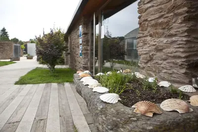 a stone retaining wall with shells in front of a building at Albergue Turistico Salceda in Salceda
