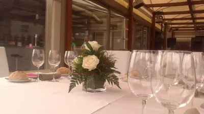 a table with wine glasses and a vase with flowers at Albergue Turistico Salceda in Salceda