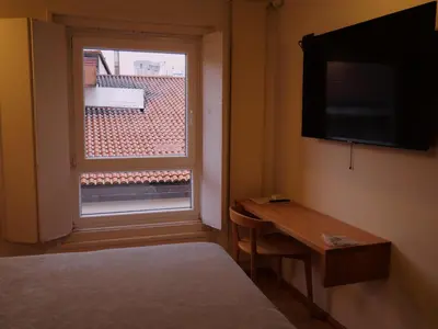 a room with a window and a desk and a television at Hotel Zarampallo in Ourense