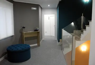 a hallway with a blue ottoman and a stair case at Hotel Altiana in Ourense