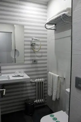 a bathroom with a sink and a toilet and a mirror at Hotel Altiana in Ourense