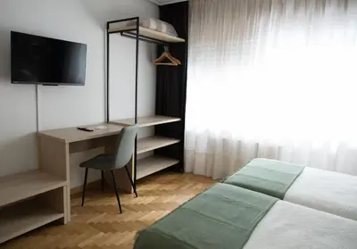a bedroom with a bed and a desk with a television at Hotel El Molinón in Cangas del Narcea