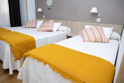 two beds in a hotel room with yellow blankets at Hotel El Molinón in Cangas del Narcea