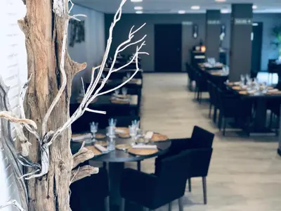 a restaurant with black tables and black chairs and branches at Hotel rural Finca Vivaldi Nature & Spa in San Miguel de las Dueñas