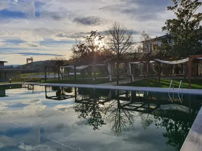 a swimming pool with the sun setting in the background at Hotel rural Finca Vivaldi Nature & Spa in San Miguel de las Dueñas
