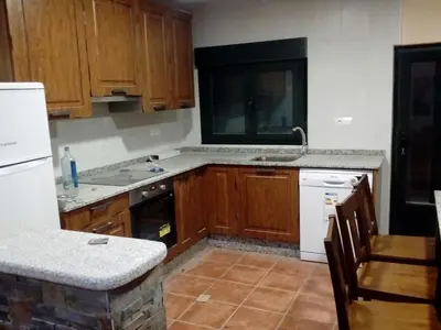 a kitchen with wooden cabinets and white appliances at Casa Rosi. Cumbres borrascosas Brañuelas in Villagatón