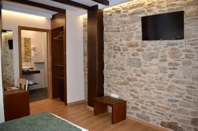 a room with a stone wall with a television on a wall at Mapoula PR Boutique in Santiago de Compostela