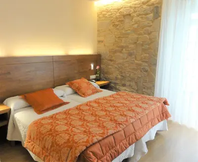 a bedroom with two beds and a stone wall at Mapoula PR Boutique in Santiago de Compostela