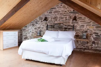 a bedroom with a large bed in a stone wall at La Rosa del Agua in El Acebo de San Miguel