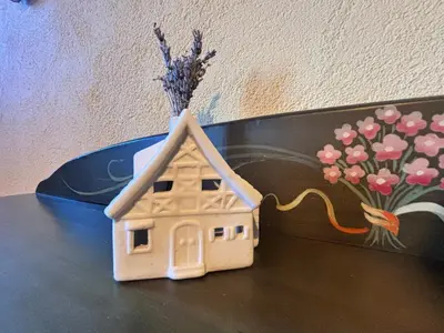 a small toy house on a table with a vase of flowers at La Rosa del Agua in El Acebo de San Miguel