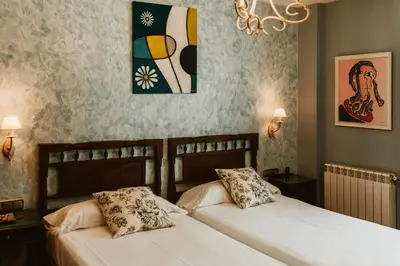 a bedroom with two beds and a painting on the wall at Casa da Capilla in Gres