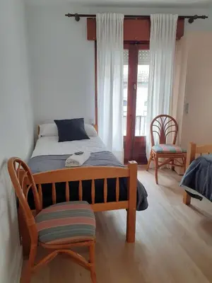 a bedroom with a bed with a chair and a window at Pensión Río Umia in Caldas de Reis