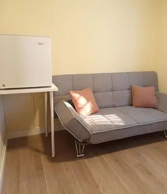 a couch with two pillows sitting next to a table at Pensión Río Umia in Caldas de Reis