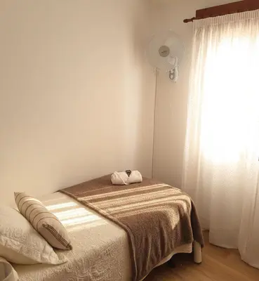 a bedroom with a bed and a window with a fan at Pensión Río Umia in Caldas de Reis