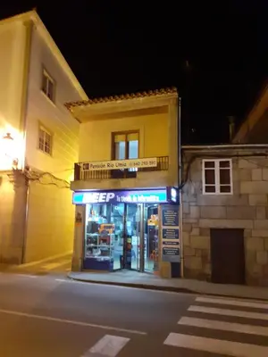a store on the corner of a street at night at Pensión Río Umia in Caldas de Reis