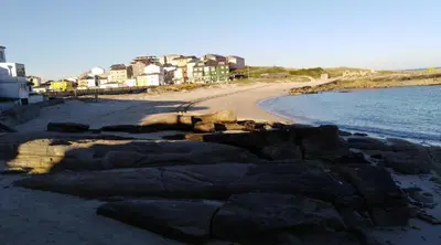 a beach with rocks and houses and the ocean at San Ciprian, belleza y tranquilidad. in San Ciprián
