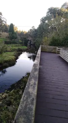 a wooden boardwalk over a river with a bridge at San Ciprian, belleza y tranquilidad. in San Ciprián