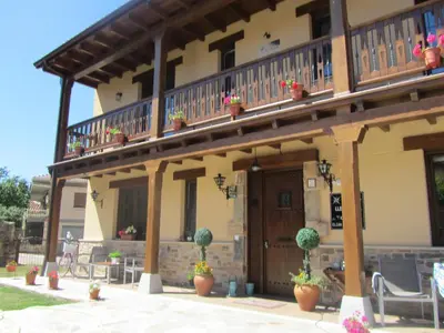 a house with a balcony and potted plants on it at La Posada de Toribia in Val de San Lorenzo