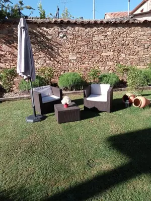 a yard with two chairs and an umbrella at La Posada de Toribia in Val de San Lorenzo