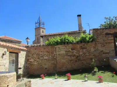 a stone wall with potted plants in front of a building at La Posada de Toribia in Val de San Lorenzo