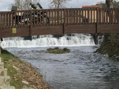 a person riding a bike on a bridge over a waterfall at La Posada de Toribia in Val de San Lorenzo