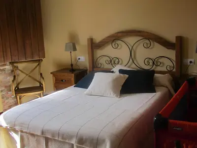 a bedroom with a large white bed with a wooden headboard at La Posada de Toribia in Val de San Lorenzo