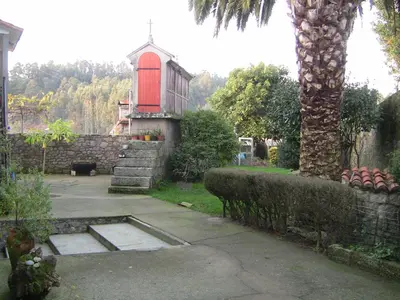 a church with a red door in a yard at Casa Xan da Pena in Villarmayor