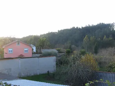 a pink house with a hill in the background at Casa Xan da Pena in Villarmayor
