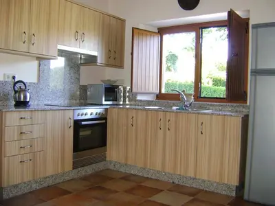 a kitchen with wooden cabinets and a sink and a window at Stone Cottage FISTERRA in Curtis