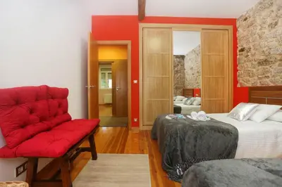 a room with two beds and a red couch at A Casa do Avó in Palas de Rei