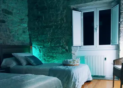 a bedroom with two beds and a stone wall at A Casa do Avó in Palas de Rei