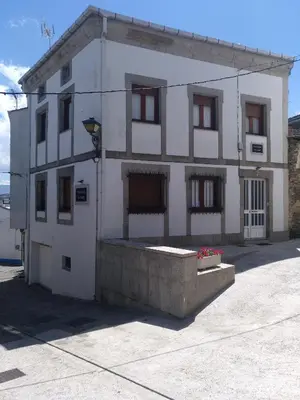 a small white building with a lot of windows at Travesia Rooms in Sarria