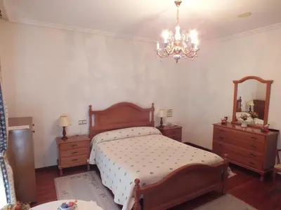 a bedroom with a bed and two dressers and a chandelier at Hotel Pousada Vicente Risco in Castro Caldelas