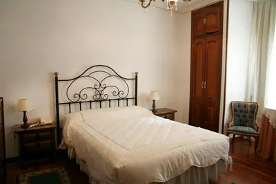 a bedroom with a large bed and a chair at Hotel Pousada Vicente Risco in Castro Caldelas