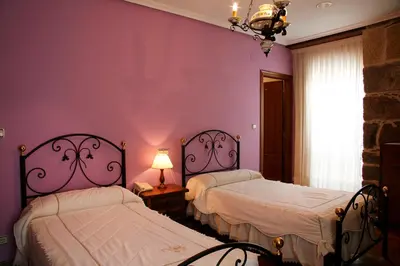two beds in a room with purple walls at Hotel Pousada Vicente Risco in Castro Caldelas
