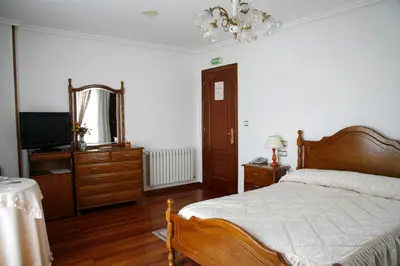 a bedroom with a bed and a dresser and a mirror at Hotel Pousada Vicente Risco in Castro Caldelas