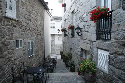 an alley with tables and chairs in an old building at Hotel Pousada Vicente Risco in Castro Caldelas